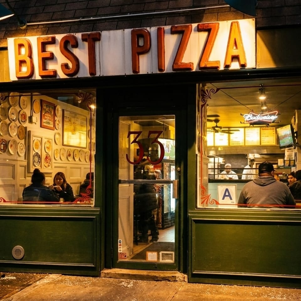 Exterior view of "BEST PIZZA" restaurant at night, with customers visible inside.